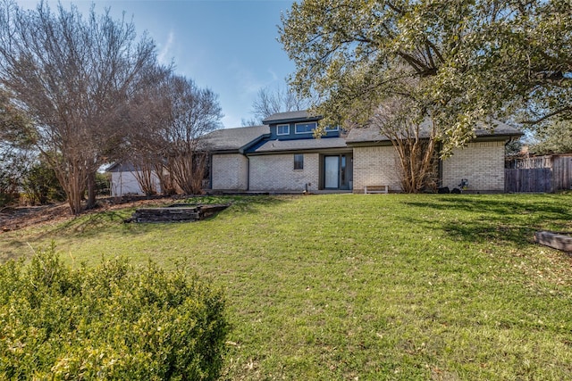 back of house with a yard, brick siding, and fence