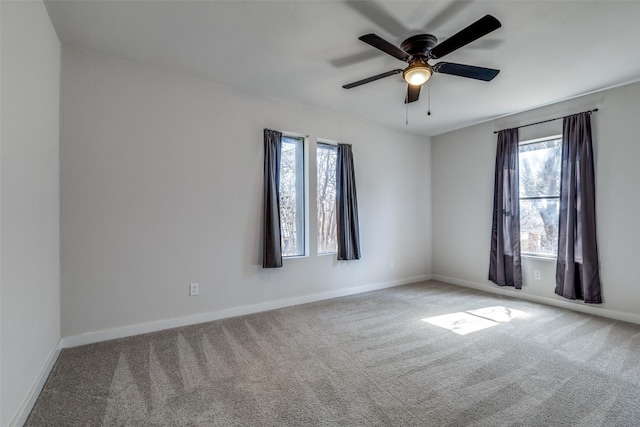 carpeted empty room with a ceiling fan and baseboards