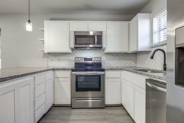 kitchen featuring open shelves, appliances with stainless steel finishes, white cabinets, and a sink