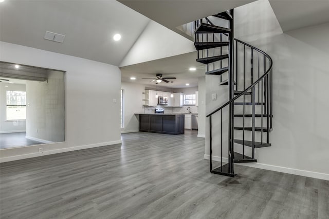 unfurnished living room with stairway, baseboards, visible vents, and wood finished floors