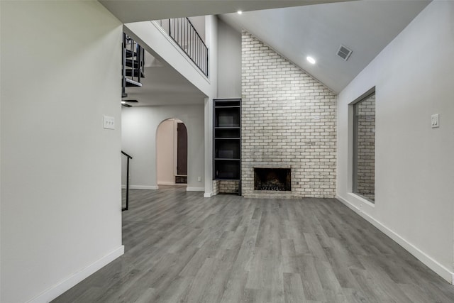 unfurnished living room with high vaulted ceiling, light wood-type flooring, visible vents, and baseboards