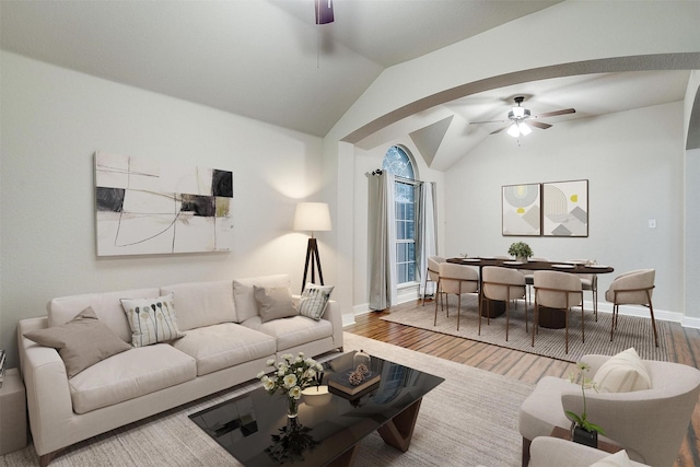 living area featuring lofted ceiling, baseboards, a ceiling fan, and wood finished floors