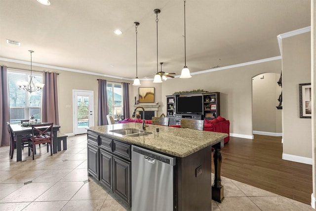 kitchen with visible vents, arched walkways, a kitchen island with sink, stainless steel dishwasher, and a sink