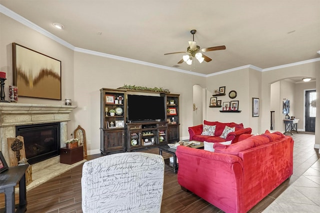 living area featuring crown molding, arched walkways, wood finished floors, and a glass covered fireplace