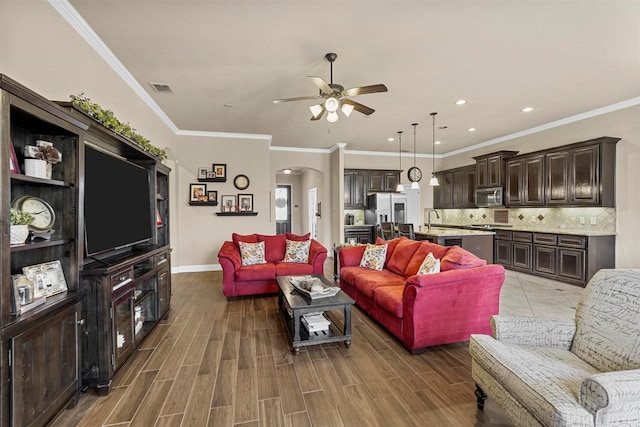 living area with baseboards, visible vents, a ceiling fan, arched walkways, and wood finished floors