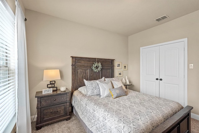 bedroom featuring baseboards, visible vents, a closet, and light colored carpet