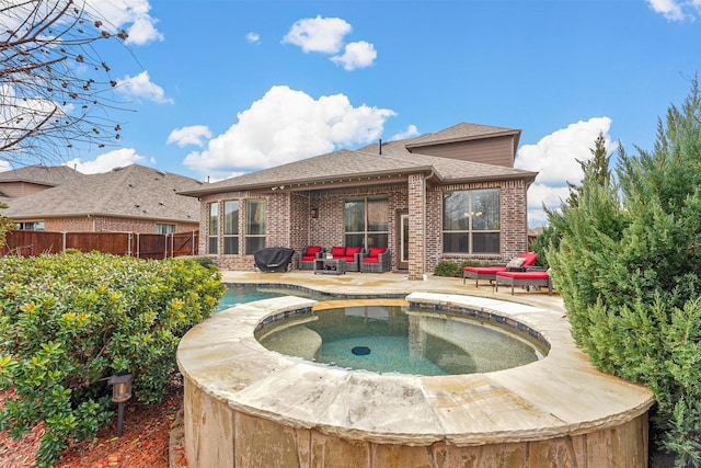 rear view of property with brick siding, a patio area, fence, an in ground hot tub, and an outdoor pool