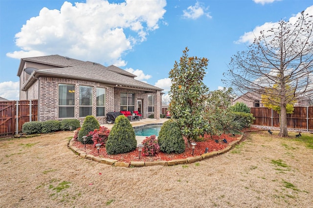 back of property with a fenced in pool, brick siding, a patio, a lawn, and a fenced backyard