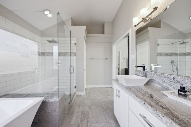 bathroom featuring double vanity, a stall shower, a sink, and a soaking tub