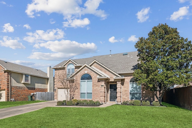 view of front of home with brick siding, fence, concrete driveway, roof with shingles, and a front yard