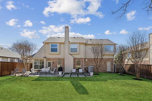 back of property featuring brick siding, a lawn, a fenced backyard, a patio area, and stucco siding