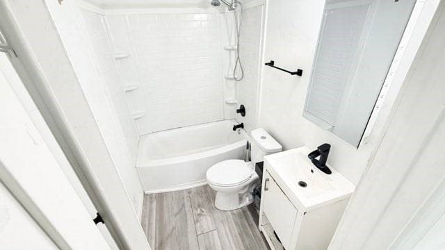 bathroom with shower / bath combination, vanity, toilet, and wood finished floors