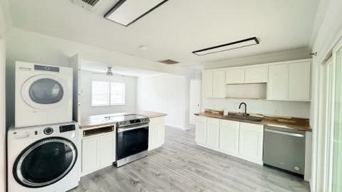 laundry area featuring laundry area, visible vents, stacked washer and clothes dryer, light wood-type flooring, and a sink