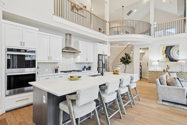 2840 Killdeer Trl, Prosper, TX 75078 - kitchen with wall chimney exhaust hood, stainless steel appliances, a sink, high vaulted ceiling, and a kitchen breakfast bar