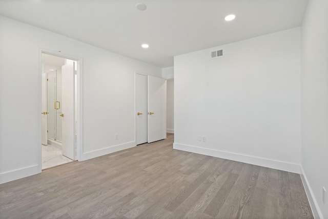 spare room with light wood-type flooring, baseboards, and visible vents