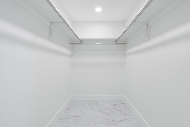 walk in closet featuring marble finish floor