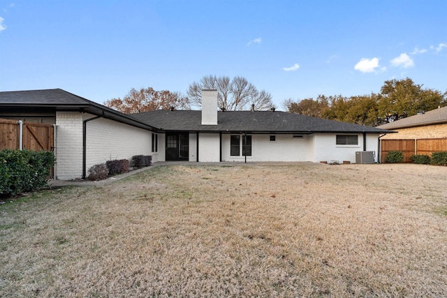 rear view of house with a yard, fence, and brick siding