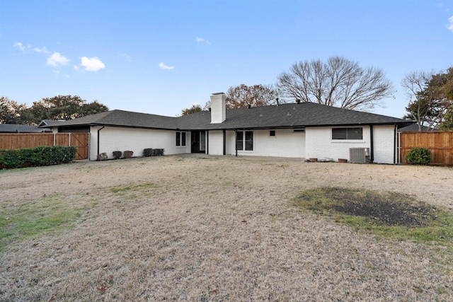 rear view of property with central AC, fence, and brick siding