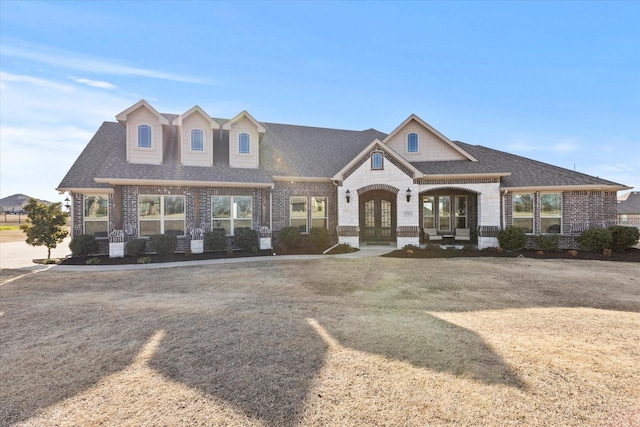 view of front of house featuring french doors, roof with shingles, and brick siding