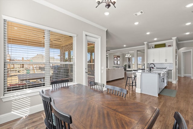 dining room featuring dark wood-style floors, arched walkways, crown molding, visible vents, and a chandelier