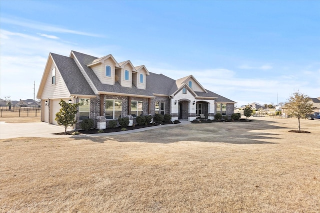 view of front of property featuring brick siding, driveway, a front lawn, and roof with shingles