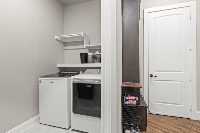 washroom with wood finished floors, laundry area, baseboards, and separate washer and dryer