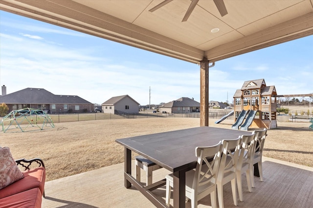 view of patio / terrace with outdoor dining space, a playground, ceiling fan, and a fenced backyard