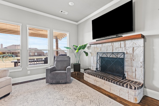 interior space featuring a fireplace, crown molding, visible vents, wood finished floors, and baseboards