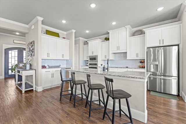 kitchen with a kitchen island with sink, white cabinets, french doors, appliances with stainless steel finishes, and dark wood finished floors