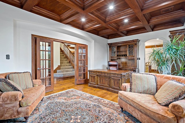 living area featuring beam ceiling, french doors, light wood finished floors, ornamental molding, and coffered ceiling