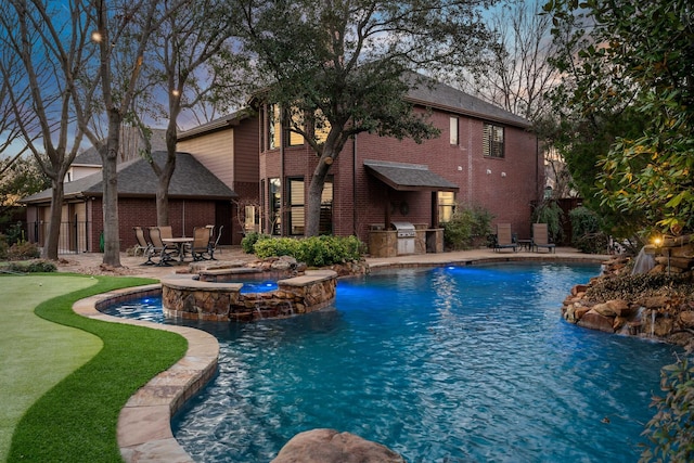 view of pool with an outdoor kitchen, area for grilling, fence, a patio area, and a pool with connected hot tub