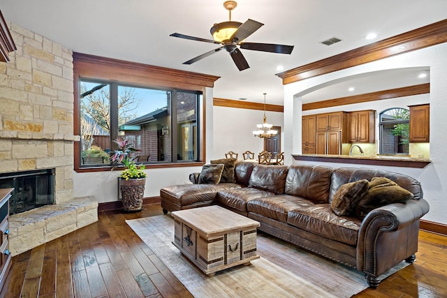 living room featuring hardwood / wood-style flooring, a fireplace, visible vents, and ornamental molding