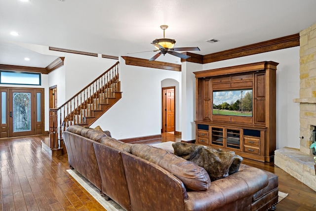 living room featuring visible vents, arched walkways, wood-type flooring, stairway, and ornamental molding