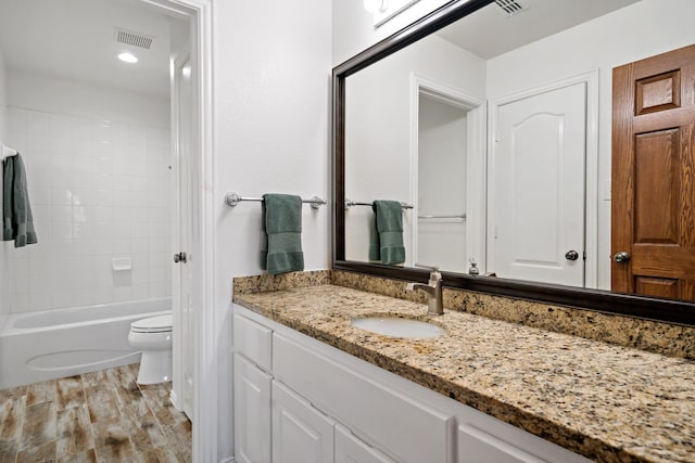 bathroom featuring shower / bath combination, visible vents, toilet, wood finished floors, and vanity