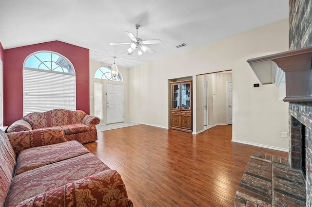 living area featuring a fireplace, lofted ceiling, a ceiling fan, wood finished floors, and baseboards