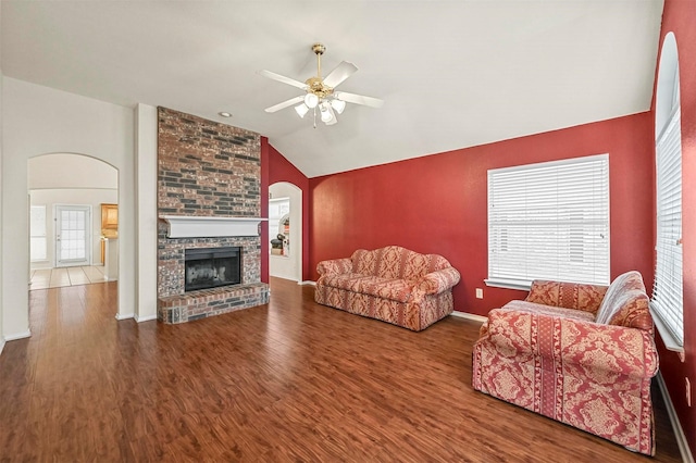 living room featuring lofted ceiling, a brick fireplace, ceiling fan, wood finished floors, and baseboards