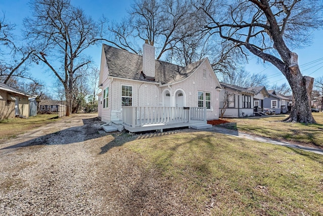 view of front of property featuring a shingled roof, a chimney, a residential view, a front yard, and brick siding