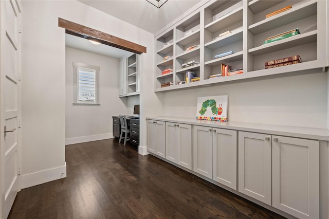 interior space featuring dark wood finished floors, built in study area, and baseboards