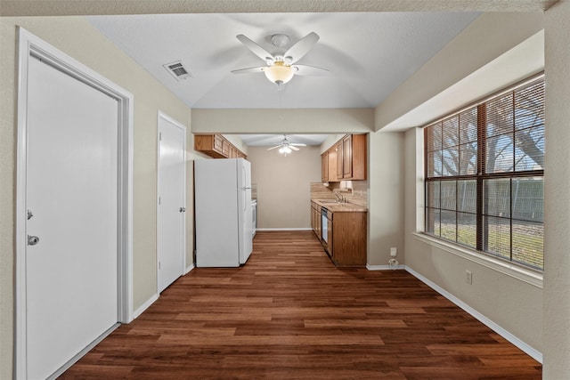 kitchen featuring a sink, baseboards, light countertops, freestanding refrigerator, and dark wood finished floors