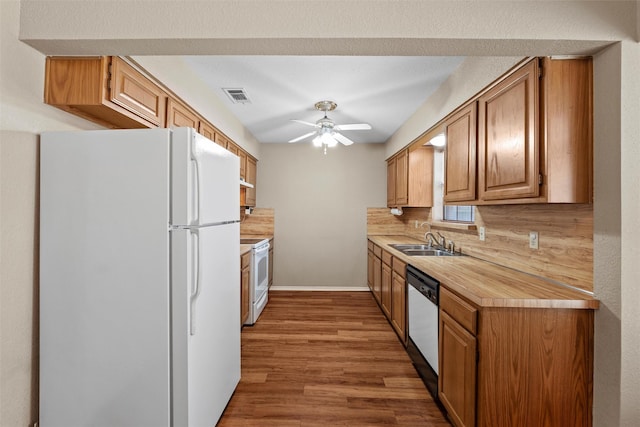 kitchen with white appliances, visible vents, wood finished floors, light countertops, and a sink