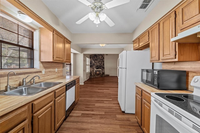 kitchen featuring white appliances, tasteful backsplash, dark wood finished floors, under cabinet range hood, and a sink