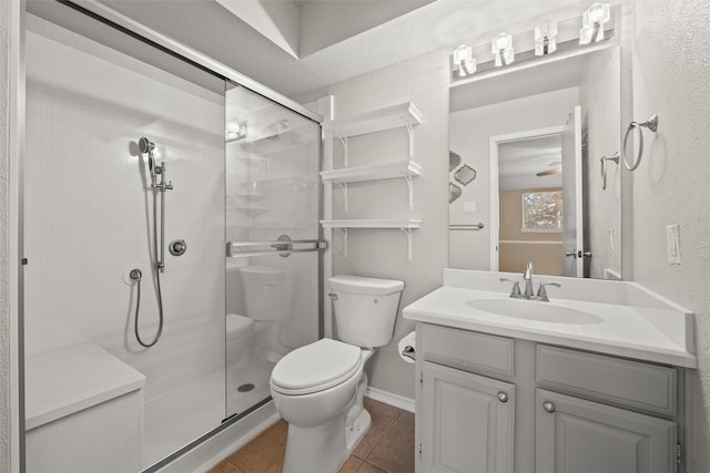 bathroom with toilet, vanity, a shower stall, baseboards, and tile patterned floors