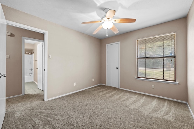 carpeted empty room featuring ceiling fan and baseboards