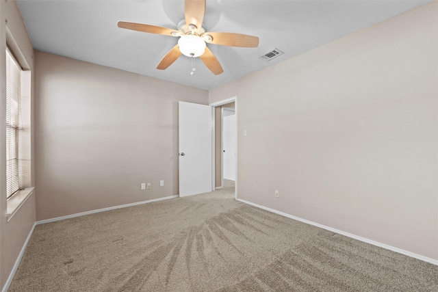 carpeted empty room with baseboards, visible vents, and a ceiling fan