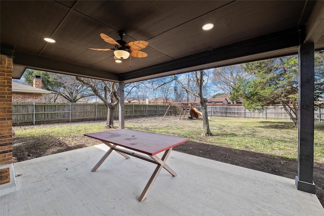 view of patio / terrace with a ceiling fan, a playground, and a fenced backyard