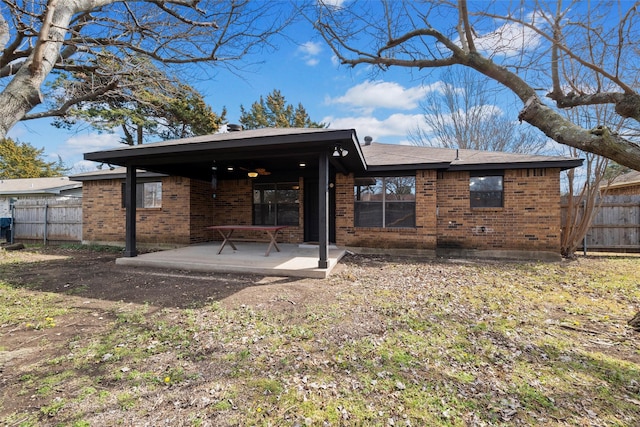 rear view of house featuring a patio area, fence, and brick siding