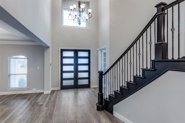 entrance foyer with ornamental molding, wood finished floors, baseboards, and a healthy amount of sunlight