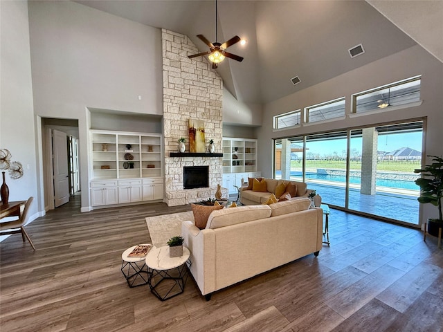 living room with visible vents, a fireplace, high vaulted ceiling, and dark wood-style flooring