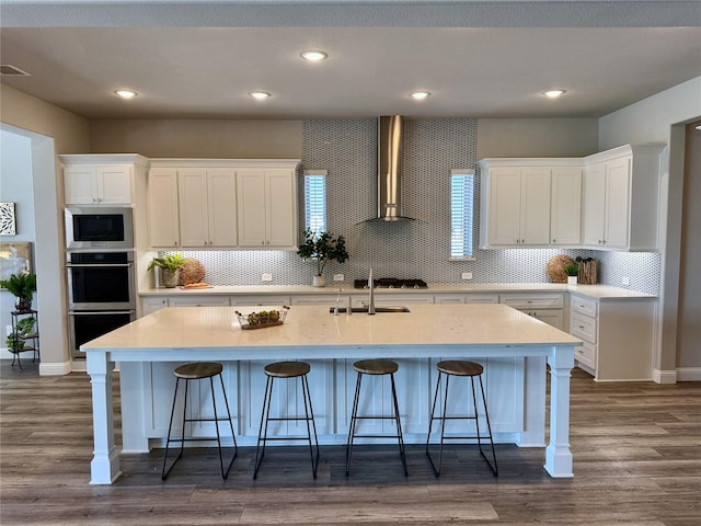 kitchen with white cabinetry, wall chimney range hood, dark wood finished floors, and stainless steel appliances