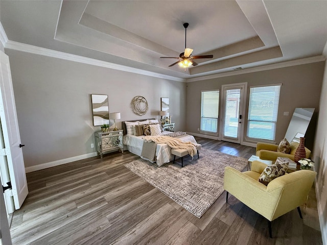 bedroom with access to exterior, baseboards, a tray ceiling, and wood finished floors